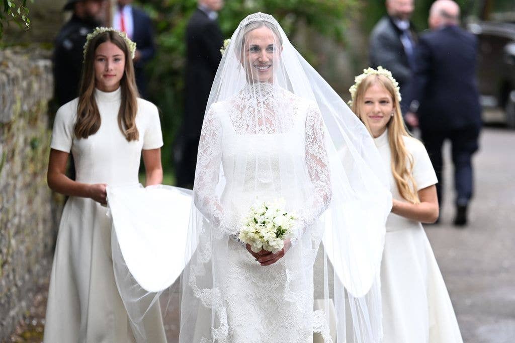 Harriet Sperling smiling wearing a white bridal gown with her three bridesmaids behind her