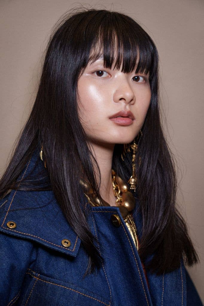 A model backstage with black hair and a fringe and dewy skin