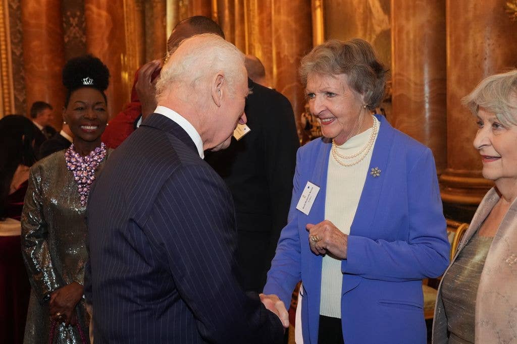 King Charles shaking hands with Penelope Keith