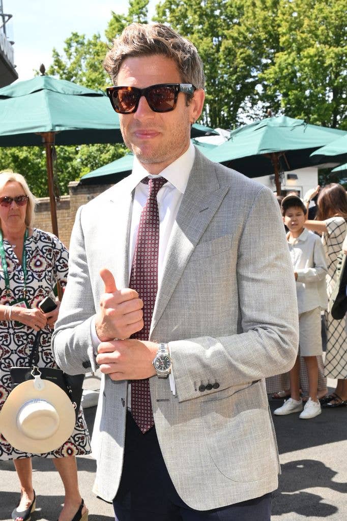 James Norton in a gray suit and red tie, giving a thumbs up.