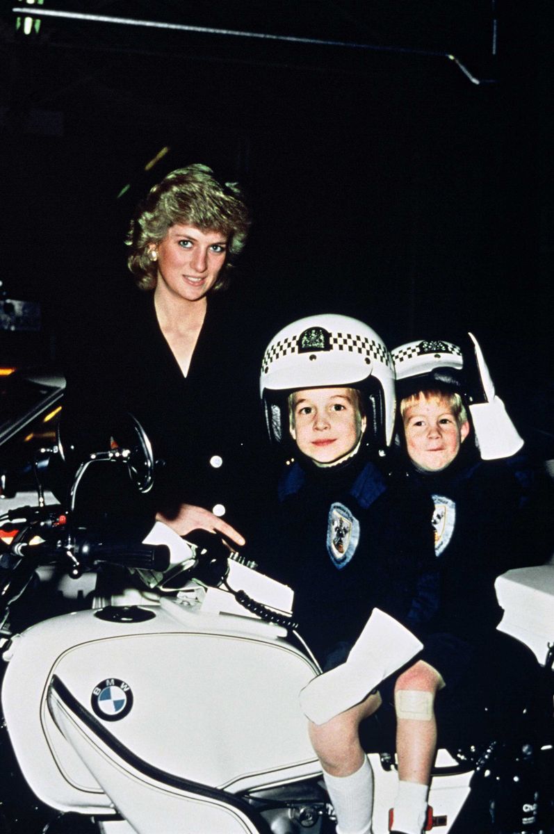 Diana, Princess of Wales, Prince William aged 5 and Prince Harry aged 3 wear police helmets as they sit on a police motorbike during a visit to a police station 