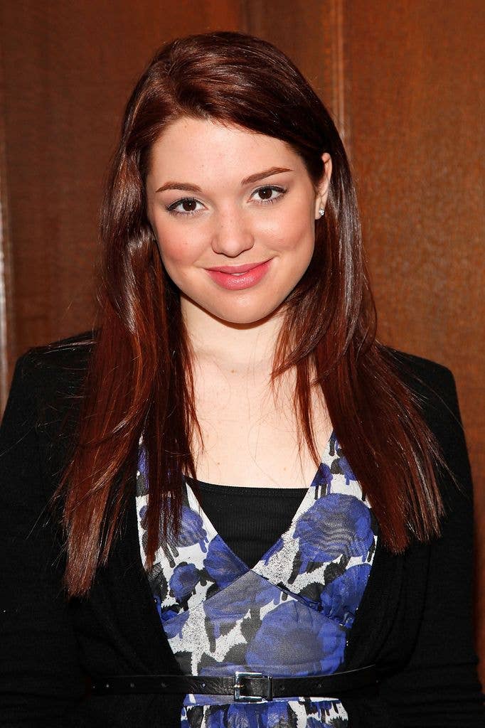 Jennifer Stone wears a black jacket, white dress with purple floral pattern and black vest top.