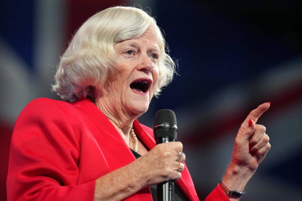 Ann Widdecombe in a red dress holding a microphone