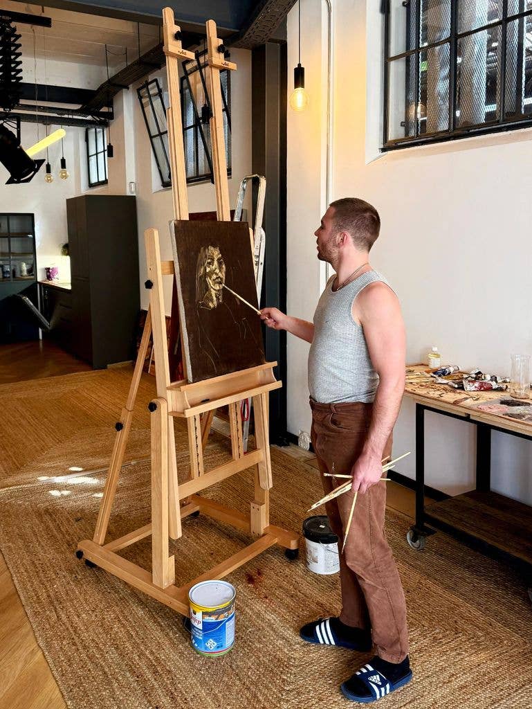 Rocco painting in gray vest and brown pants