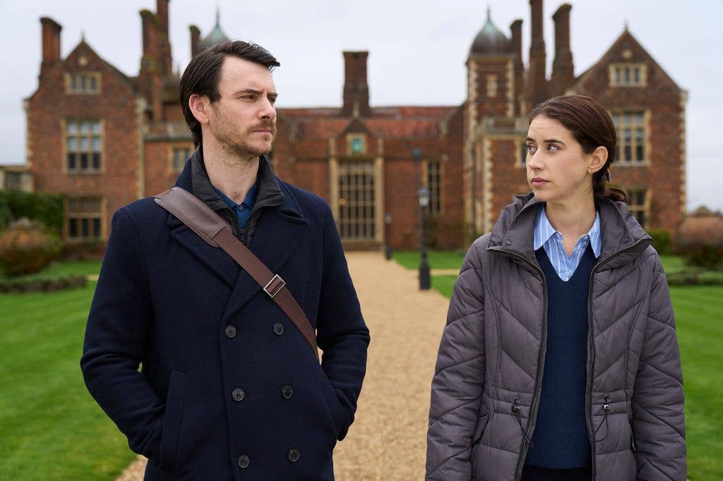 Man and woman looking at each other standing in front of country mansion