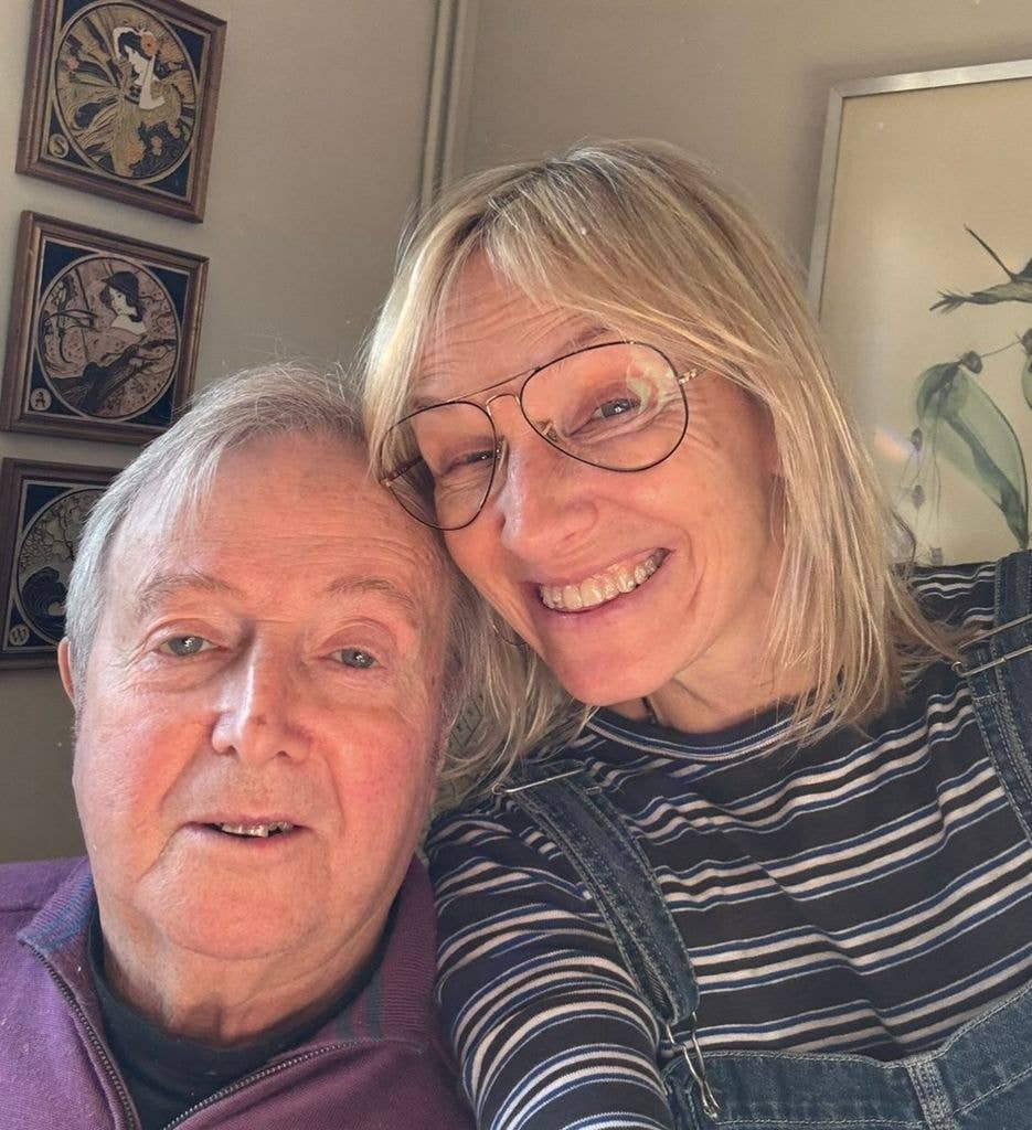 Jo Whiley and an older man in a purple jacket smile for the camera.