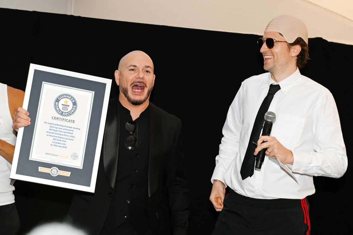 Pitbull (L) is presented with the Guinness World Record title for the 'largest gathering of people wearing bald caps' alongside BBC Radio 1 presenter Greg James