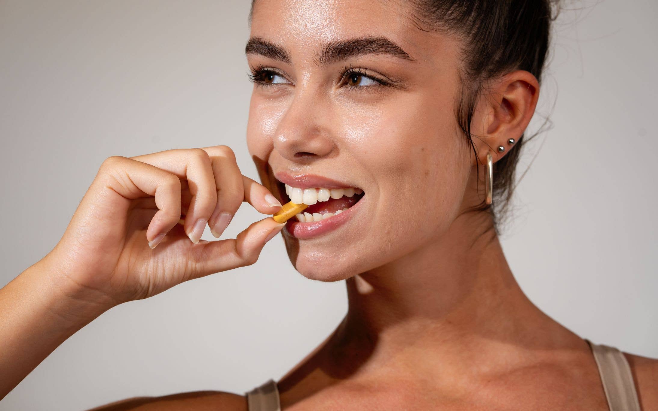 Caucasian ethnicity Attractive young adult woman taking vitamin. Studio shot, 20-25 years.