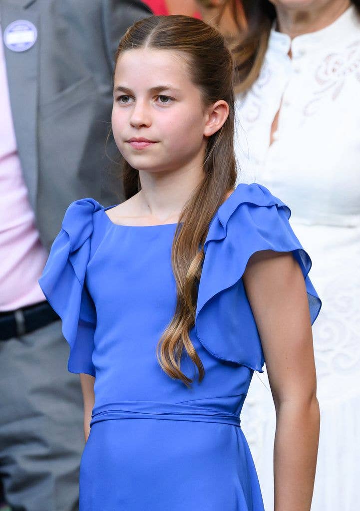 Princess Charlotte with her arms behind her back in a blue ruffled dress