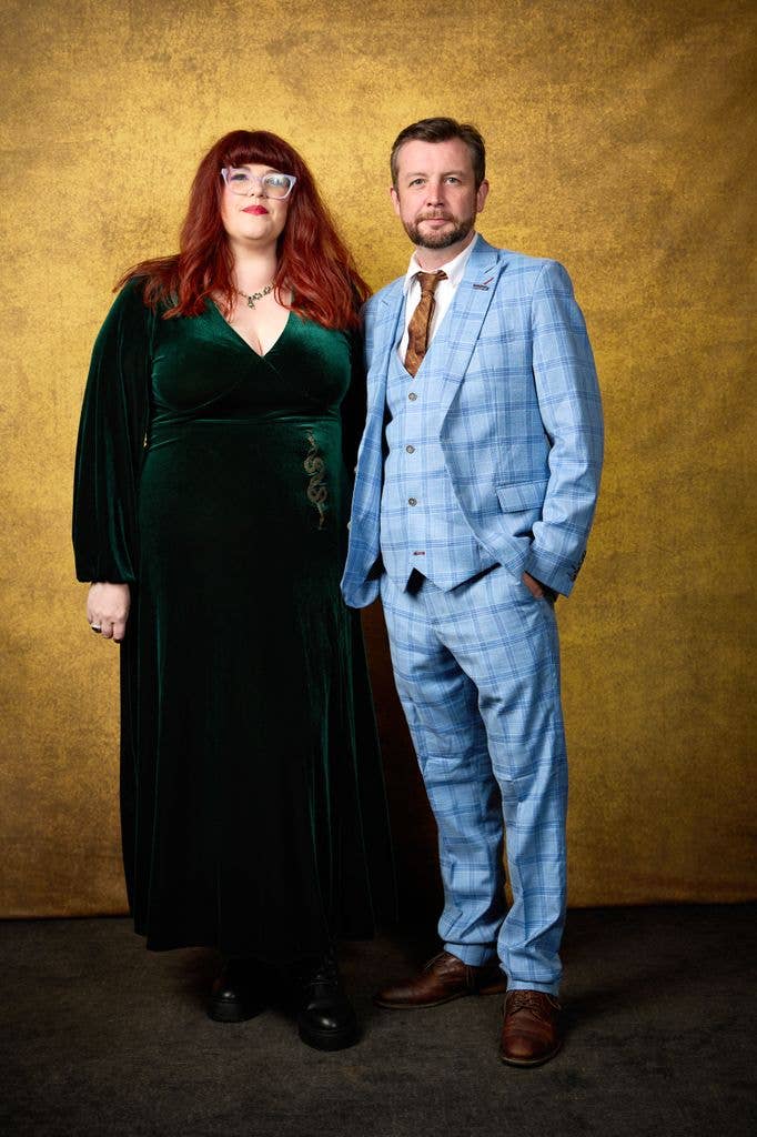 Jenny Ryan in a green dress and Thom Tuck in a blue suit stand together against a gold background.