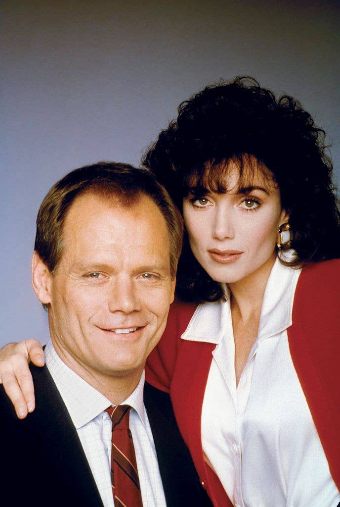 Fred Dryer and Stepfanie Kramer smiling for a photo, he in a suit, she in a red blazer.