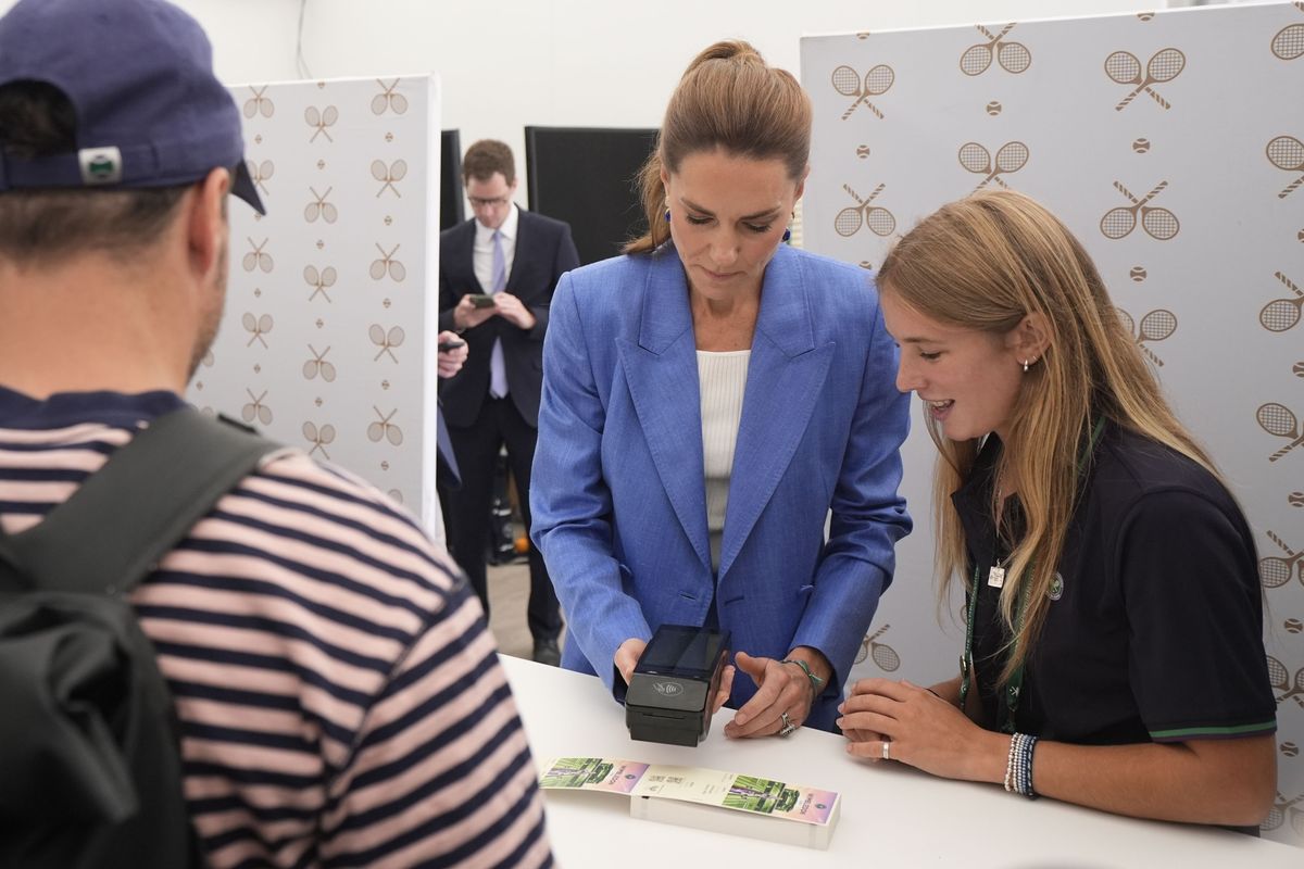 Princess Kate smiles as she chats with visitors while helping distribute tickets ahead of the day's matches.