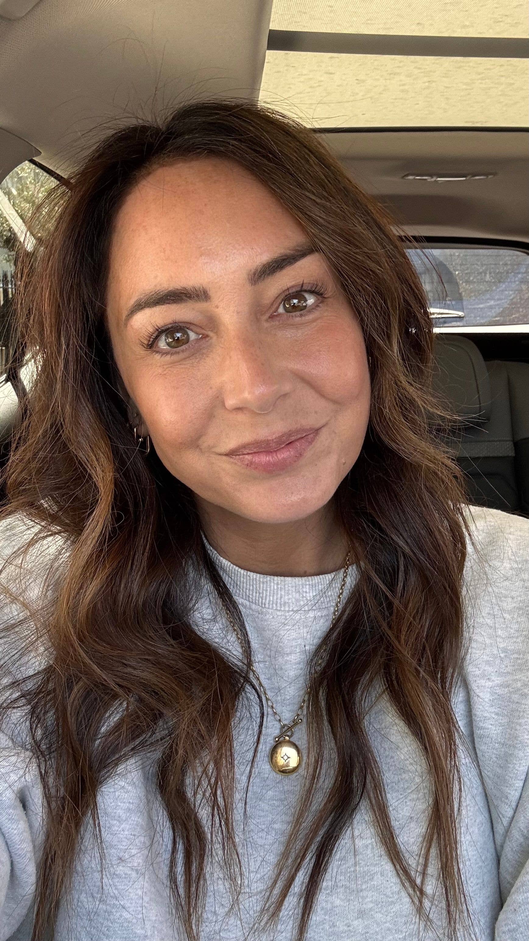 selfie of a brunette woman smiling with cream makeup