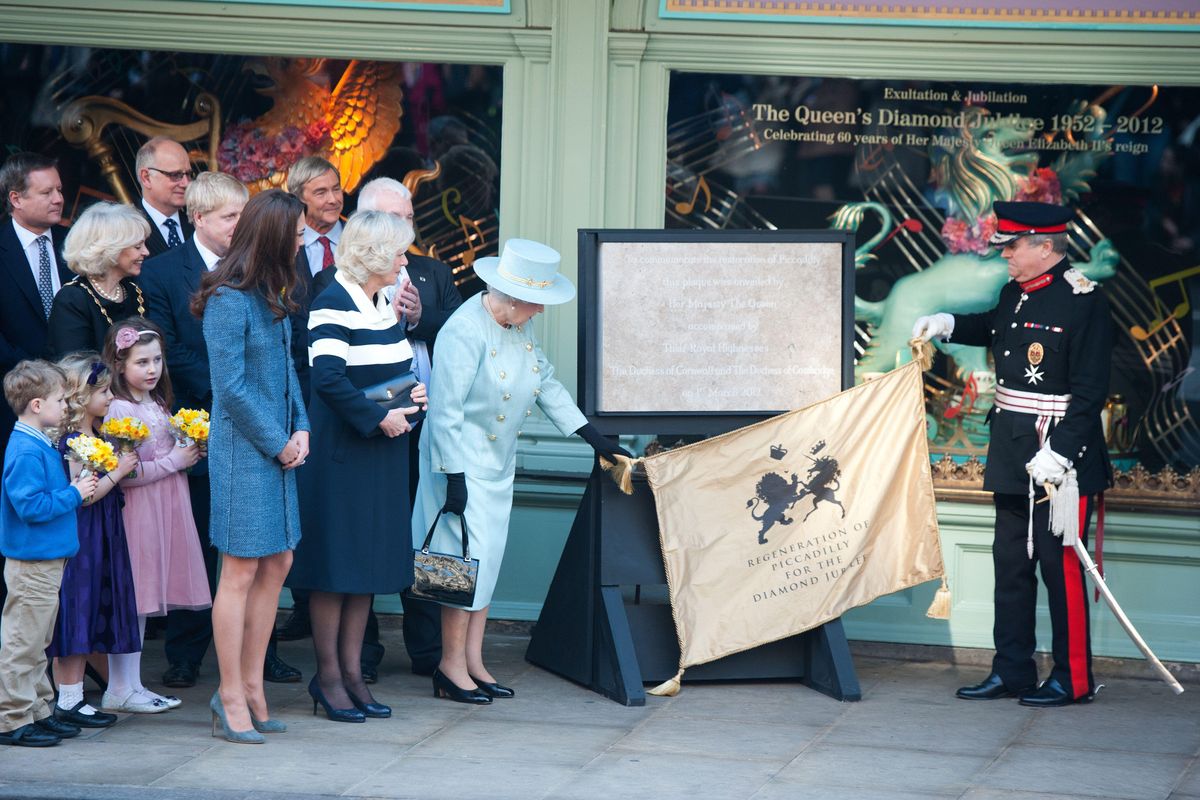 Queen Elizabeth II unveils a plaque during a visit to Fortnum & Mason in London's Piccadilly alongside Catherine, Duchess of Cambridge, and Camilla, Duchess of Cornwall, on March 1, 2012.