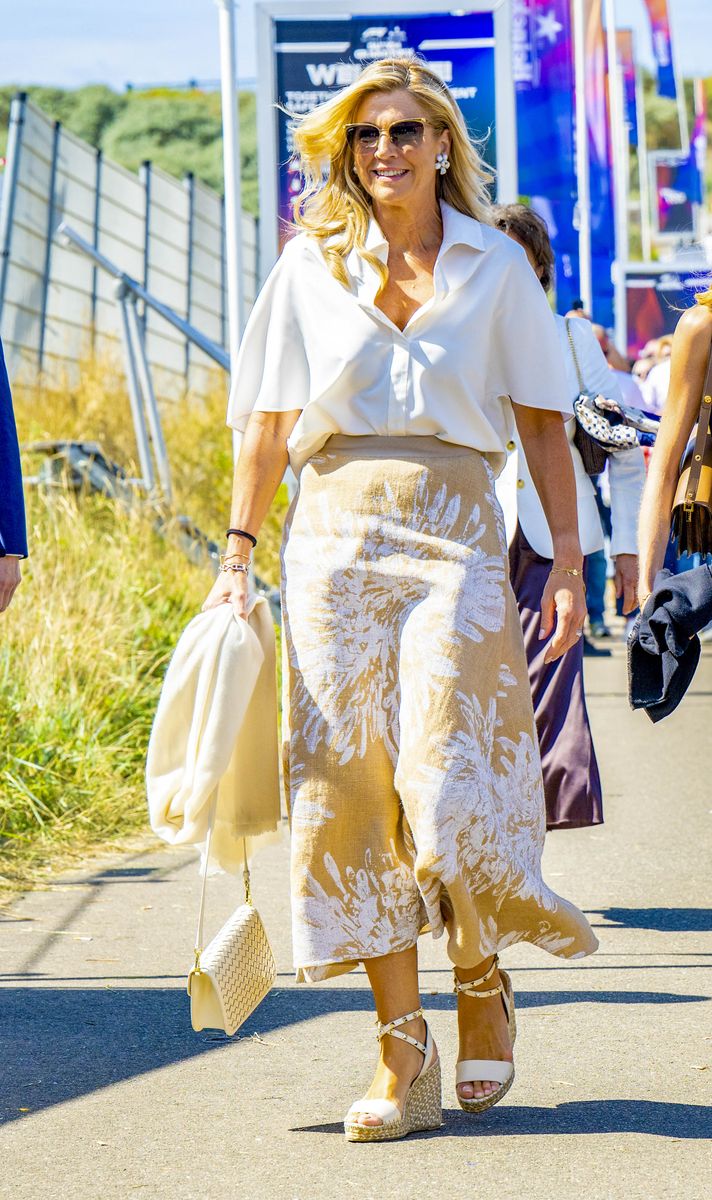 Queen Máxima embraced breezy summer style in a white blouse and floral midi skirt, finished with espadrille wedges and a woven handbag.
