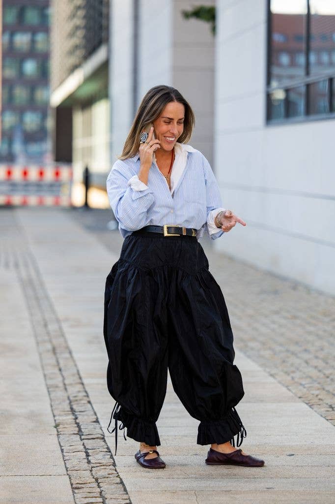 Idalia Salsamendi wears white a blue shirt and JW Anderson, black high waisted wide leg trousers Ganni, shoes Loewe, belt Alberta Ferretti, during Copenhagen Fashion Week