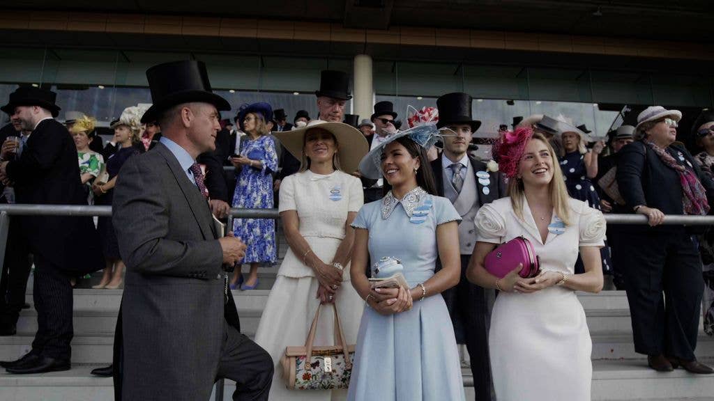 Group of people at an event, including a woman in a blue dress and a man in a gray suit.