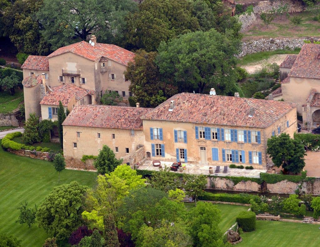 Aerial view of a large, multi-building estate with red roofs and blue shutters.