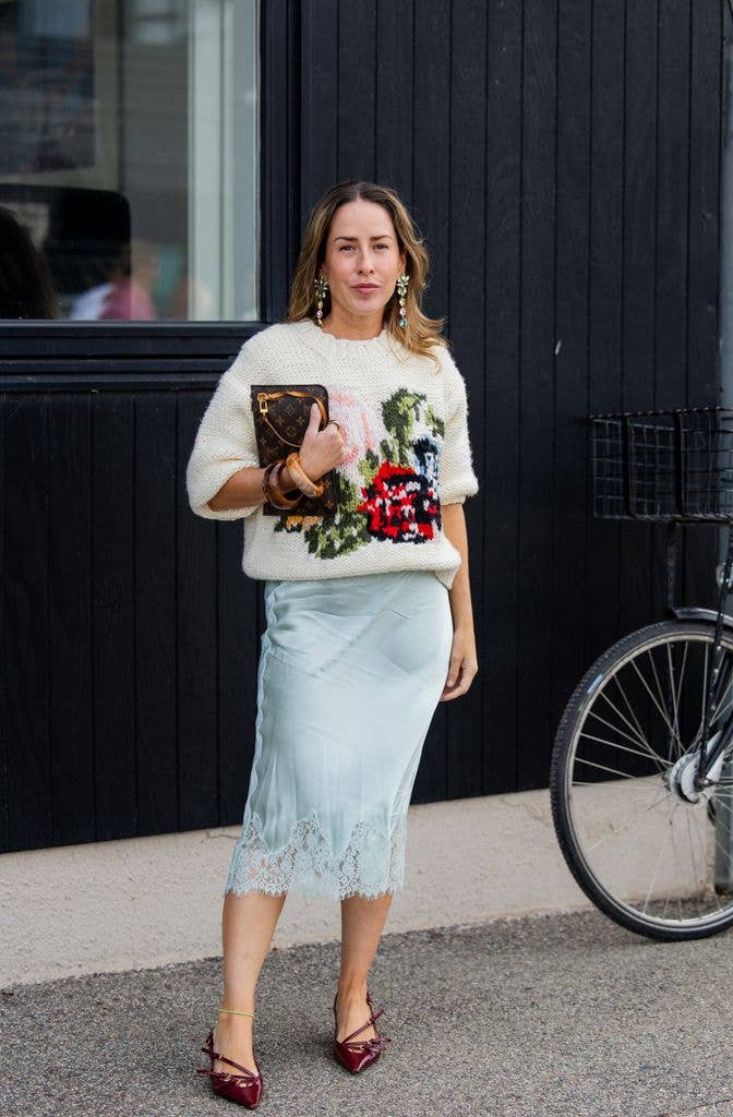 Idalia Salsamendi wears embroidered sweater, turquoise laced skirt, Louis Vuitton bag outside Stine Goya during the Copenhagen Fashion Week Spring/Summer 2027