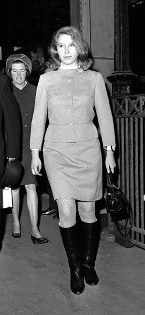 Anne, Princess Royal, in a suit and boots, walks with another woman in a hat.