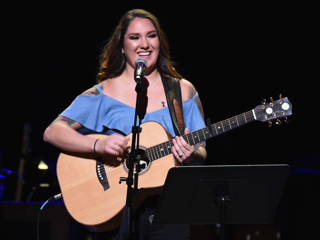 Allie Colleen on stage holding a guitar