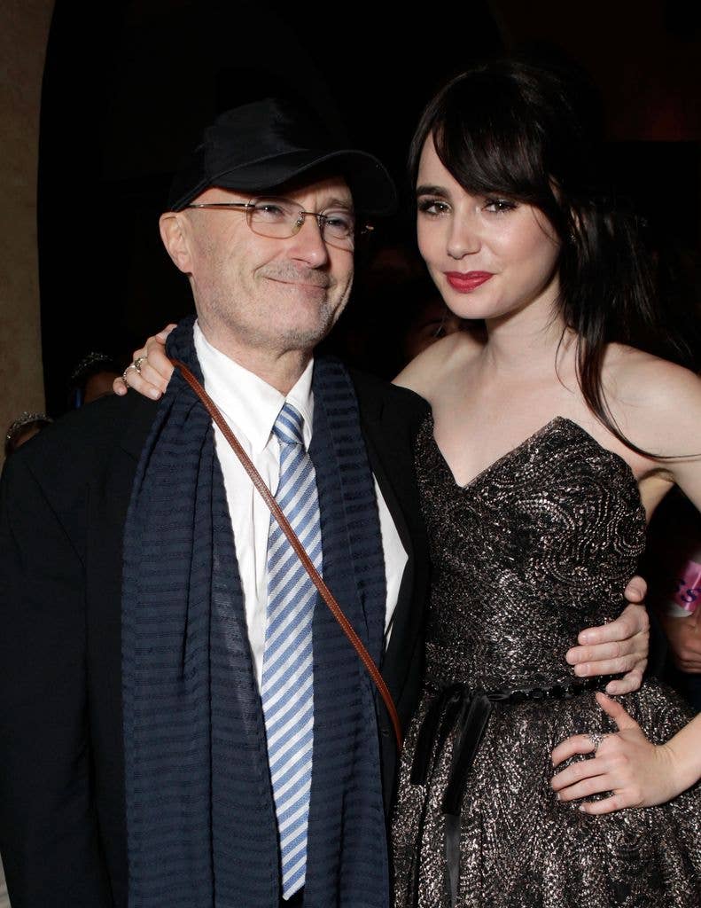Phil Collins, wearing a suit and a striped blue tie, poses with Lily in a black dress.