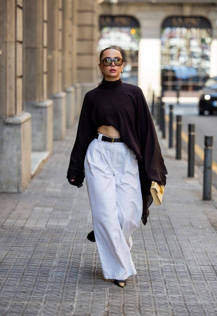 Anna Wein wears white black belted white waist pants DISSH, black wide ruffled turtleneck tap Arakii, beige bag Demellier London, heels YSL, big sunglasses VEHLA on August 10, 2026 in Barcelona, Spain. (Photo by Christian Vierig/Getty Images)