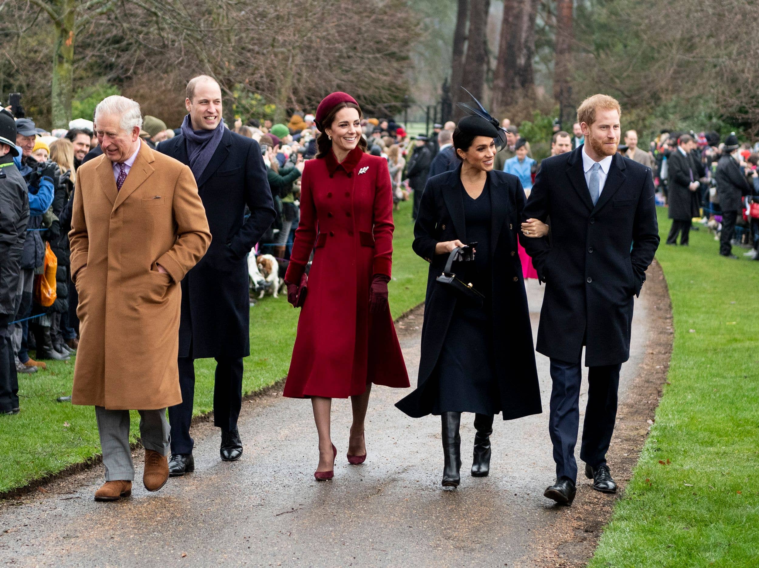 Prince Charles, Prince William, Kate Middleton, Meghan Markle, and Prince Harry walk together on a path.
