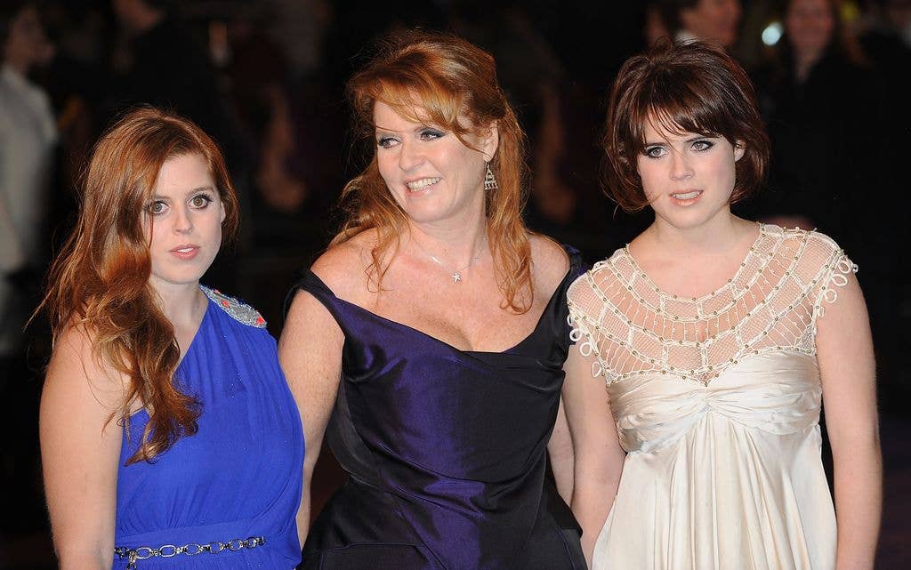 Three women standing together, the middle woman wears a black dress, the others wear blue and white dresses.
