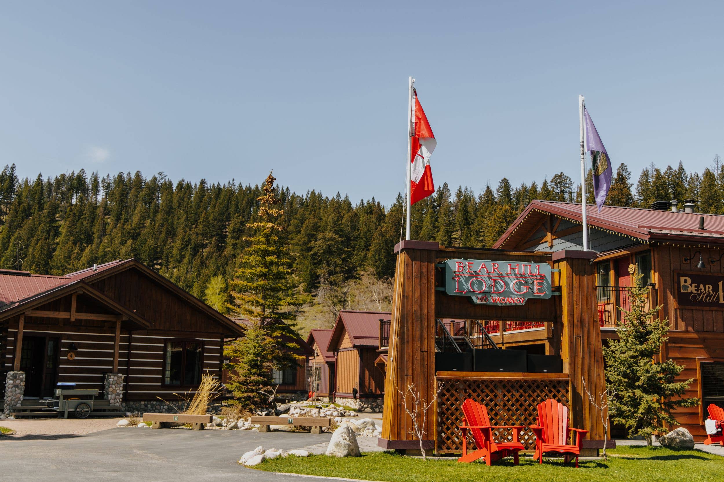 The exterior of Bear Hill Lodge in Jasper, Alberta, Canada showing the reception, one of the cabins and the Canadian flag