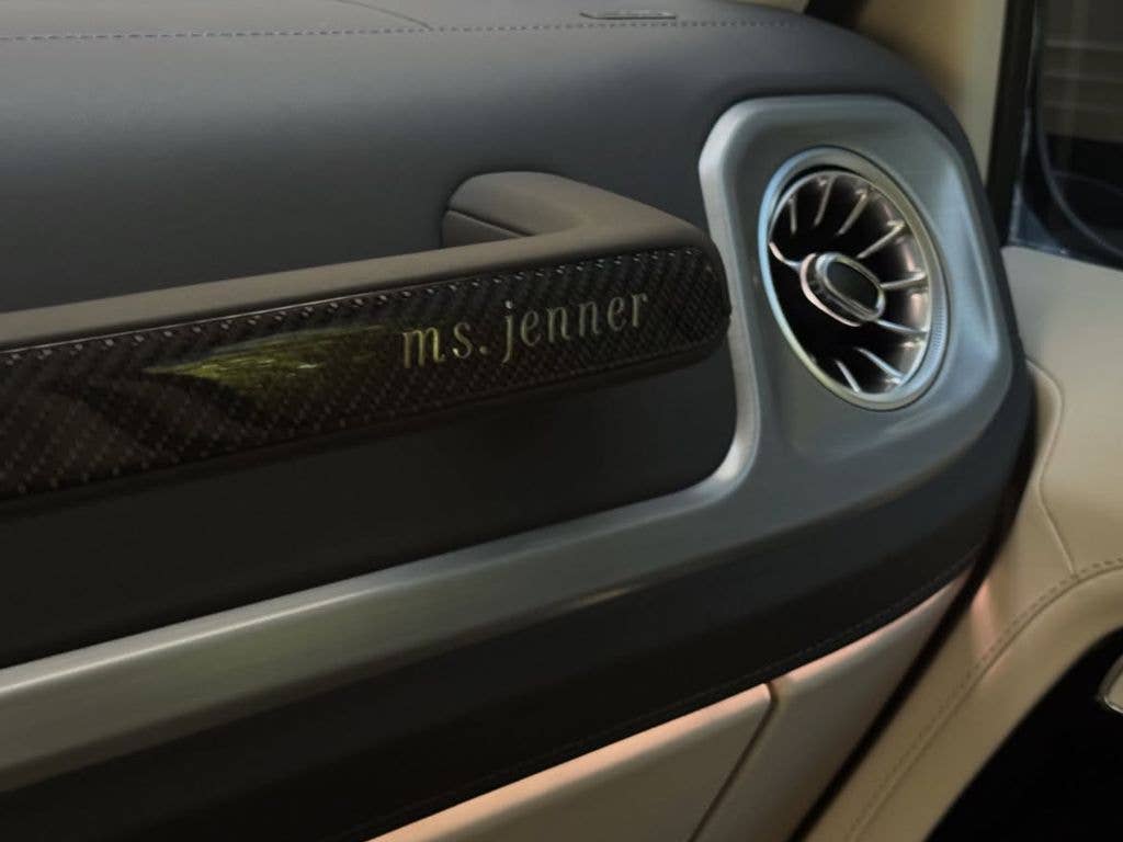 Close-up of a car's interior with 'ms. jenner' engraved on the door handle.
