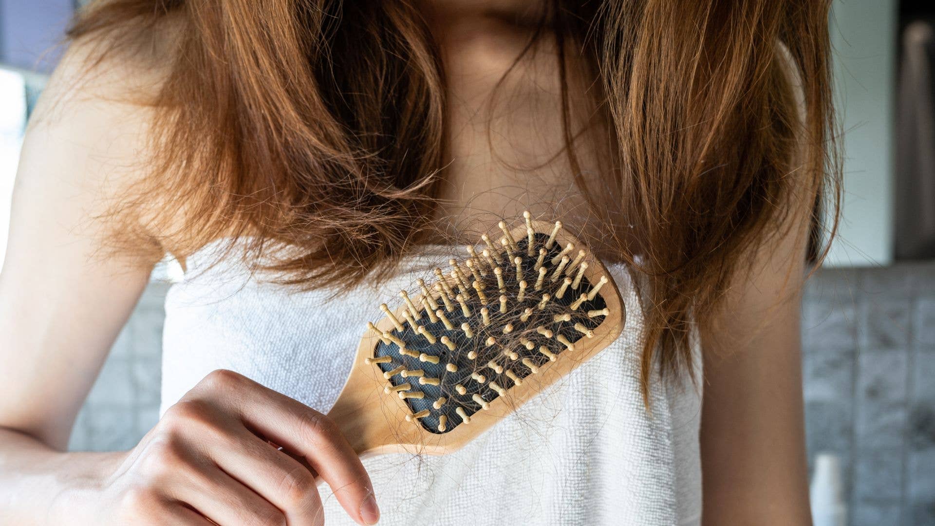 Cropped shot of woman holding comb with hair loss after brushing her hair.