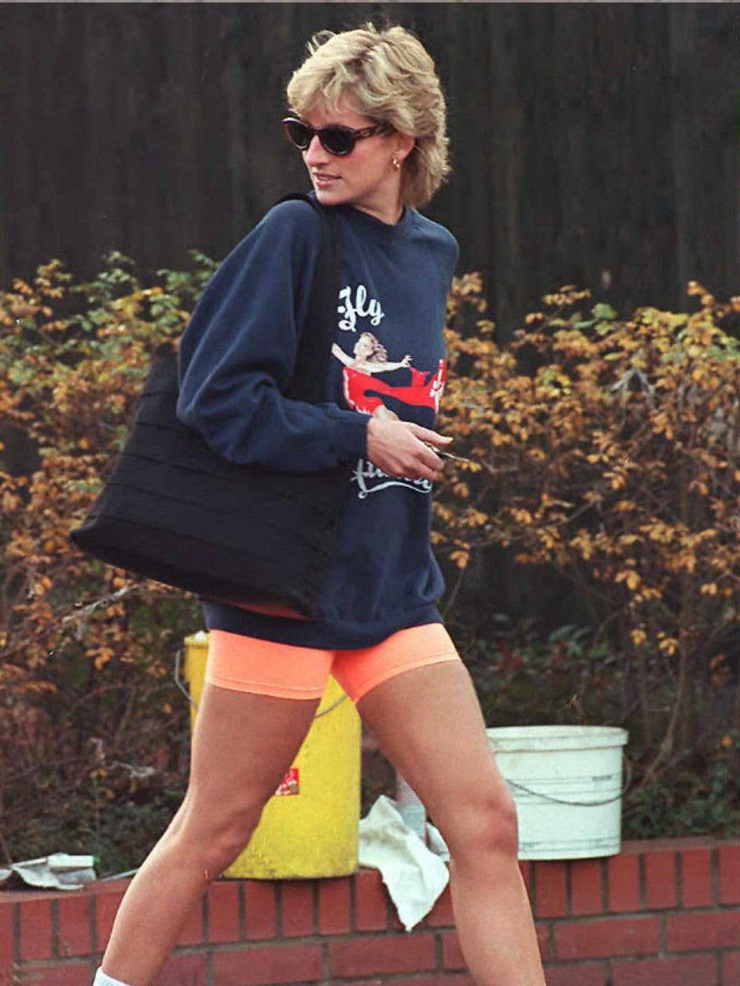 Princess Diana out and about wearing biker shorts, a crew neck hoodie and running trainers