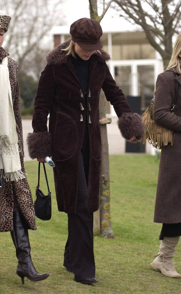 Zara Tindall walking with her head down in a cap and brown jacket