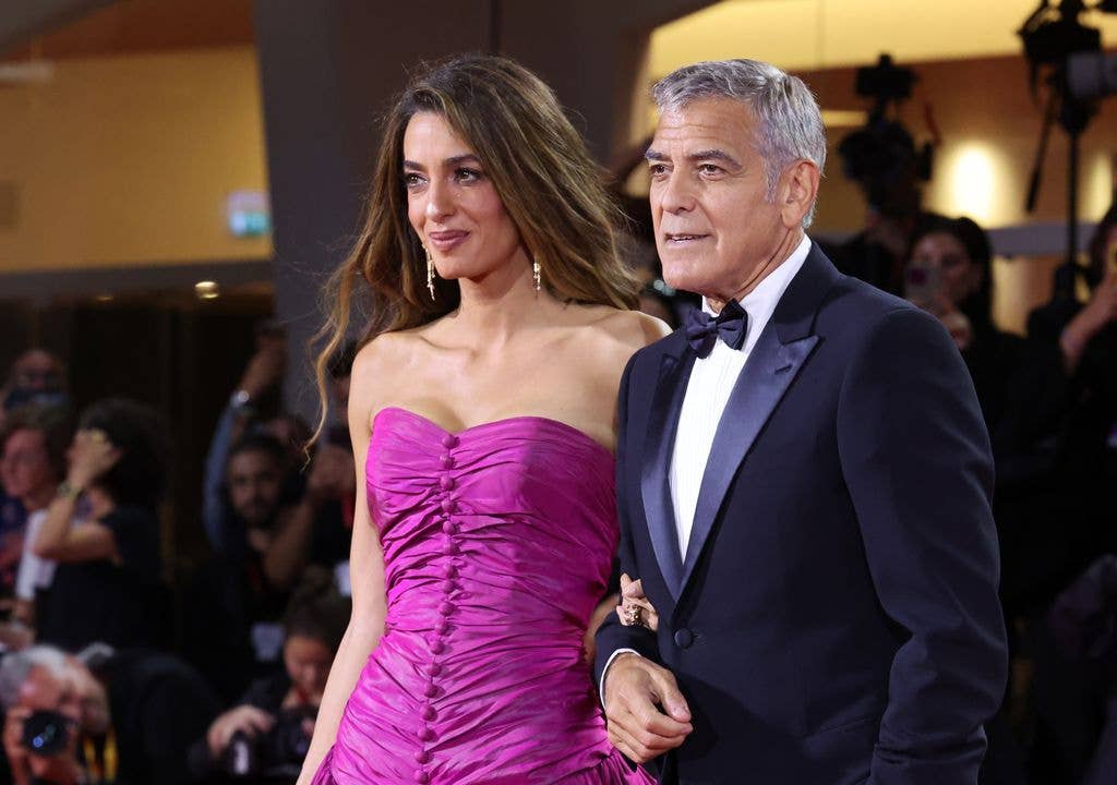 George and Amal Clooney standing together at an event, surrounded by onlookers.