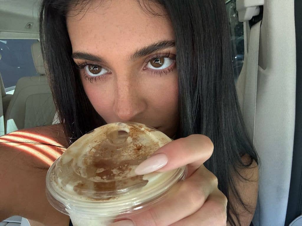 Kylie Jenner holding a cup of coffee with a cinnamon-dusted lid.