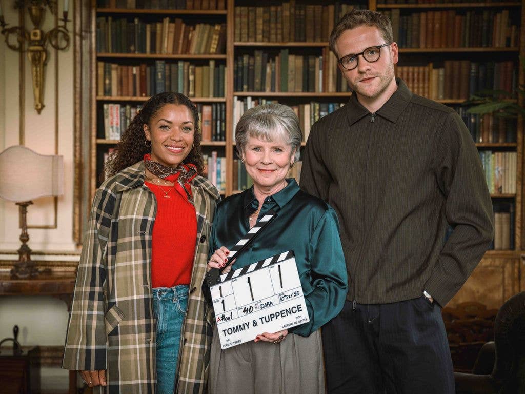 three actors standing in office library holding clapperboard