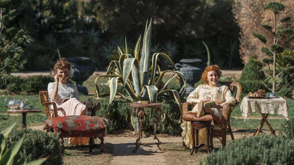 Two women (Phillipa Northeast, Kate Mulvany) sit in chairs in a garden, one with sunglasses, both smiling.