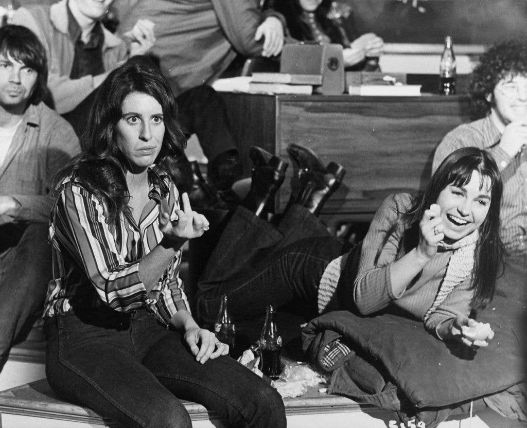 Several individuals are seated, smiling and making hand gestures in a relaxed setting.