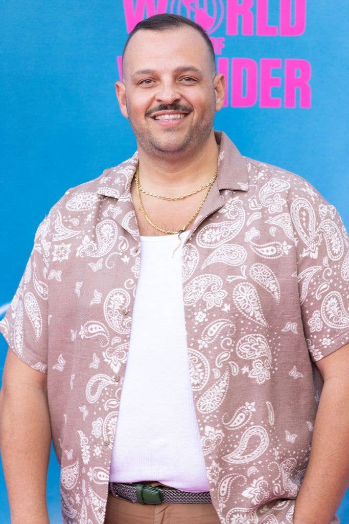 Daniel Franzese smiling, wearing a paisley shirt and gold necklace, at an event.