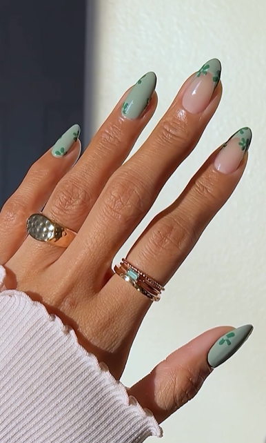 Romantic almond nails with mint green French tips and matching green floral accents, designed to elongate and streamline the hands.