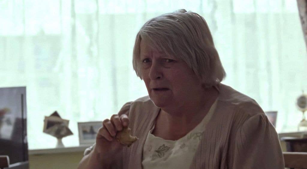 Brenda Blethyn, with short grey hair, holds a piece of food in her hand.