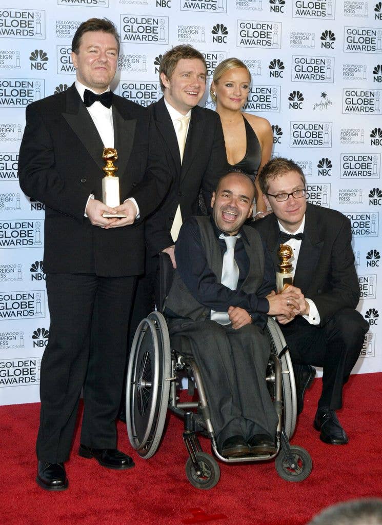 Ricky Gervais, Stephen Merchant, and Martin Freeman pose with Lucy Davis and Ash Atalla in wheelchair holding awards.