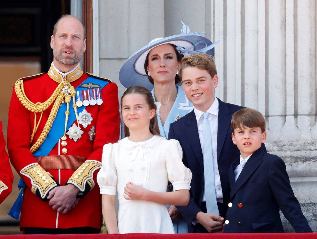 Prince William, Kate Middleton, and their three children stand together on a balcony, dressed in formal attire.