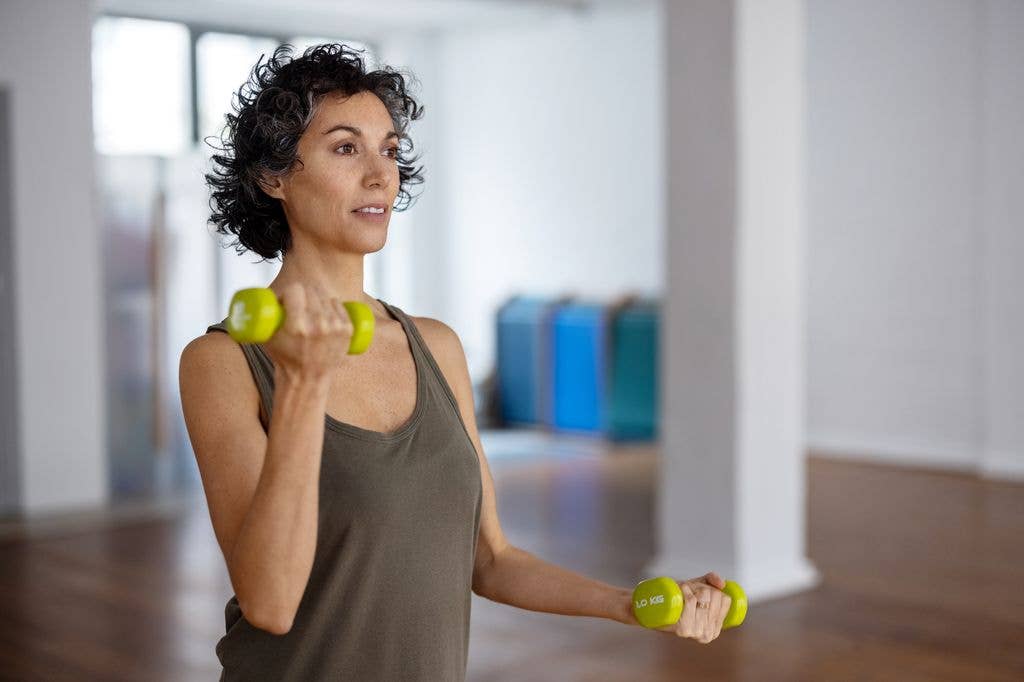 Fit mature woman doing dumbbell workout in gym