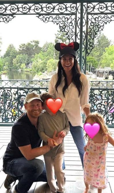 Prince Harry and Meghan, Duchess of Sussex, with their children, smiling on a balcony with a scenic view.