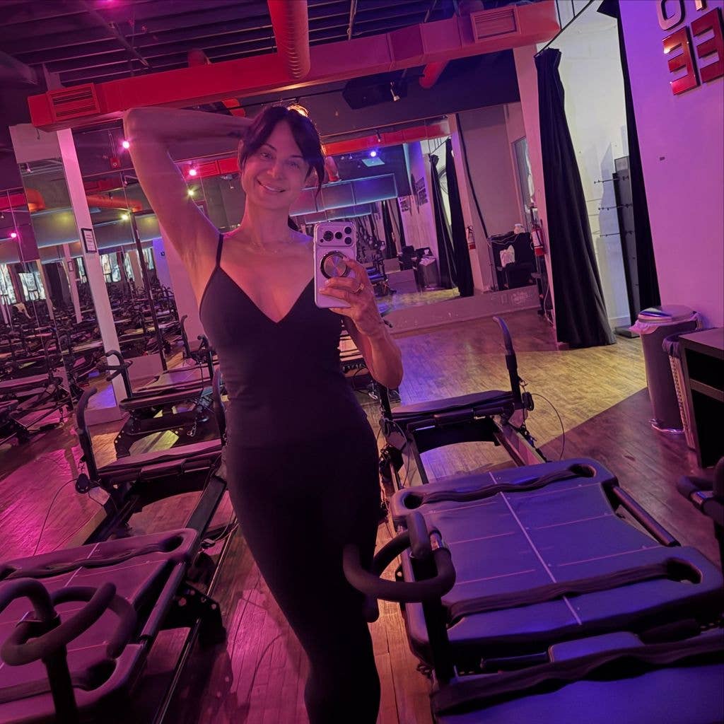 Selfie of Catherine Bell in a gym in front of reformer machine