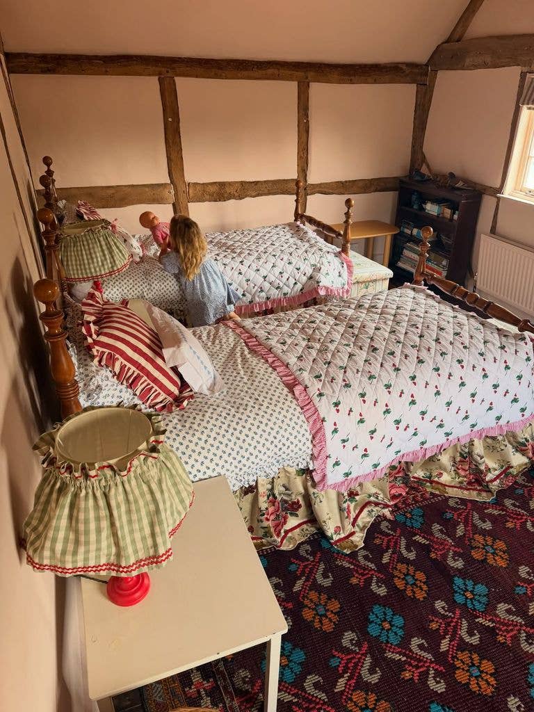 Child playing with dolls in a cozy bedroom with twin beds and floral bedding.