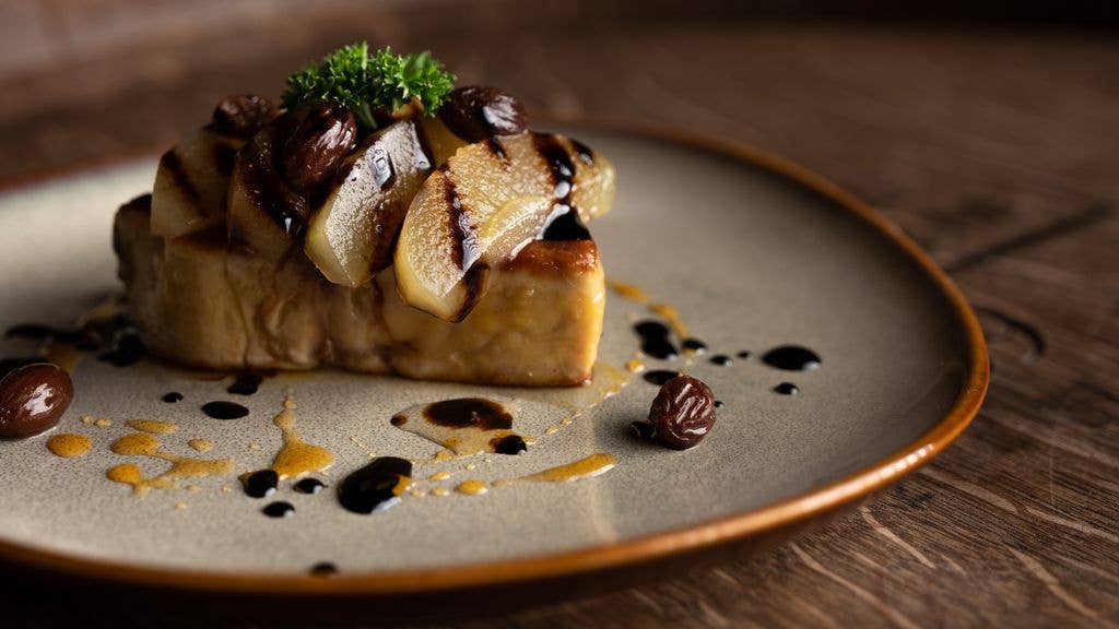 Foie gras with fruits displayed neatly on a plate.