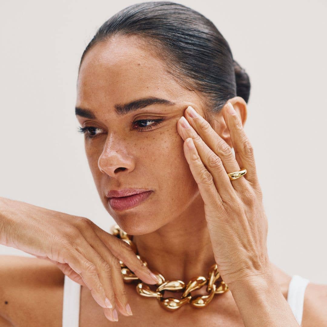 Misty Copeland with her head to the side and hands up to her face showing off her beautiful skin 